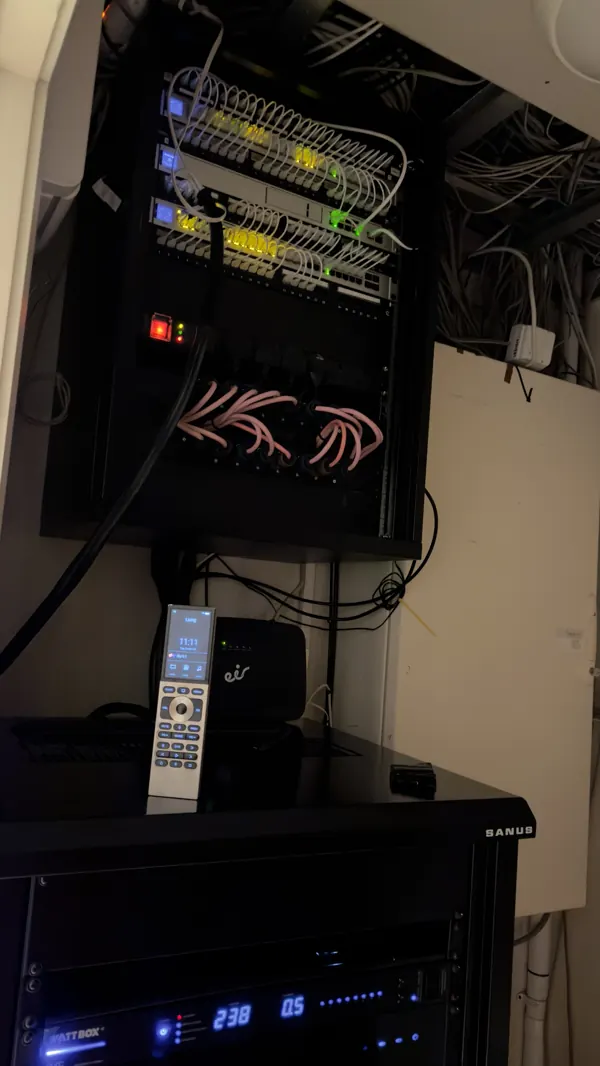 The finished wall cabinet above the equipment rack in Cork, with a Control4 handheld remote on top of the rack