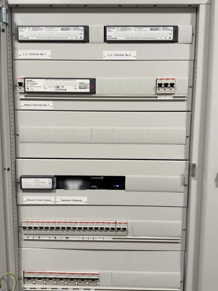 Open lighting cabinet with two Philips Dynalite L.V. dimmers and a mains dimmer at the top, units labelled network power supply and network gateway in the middle and circuit breakers below