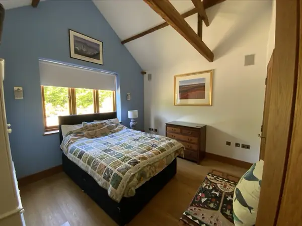 A bedroom in the house, with a roller blind and wall mounted controls beside the window