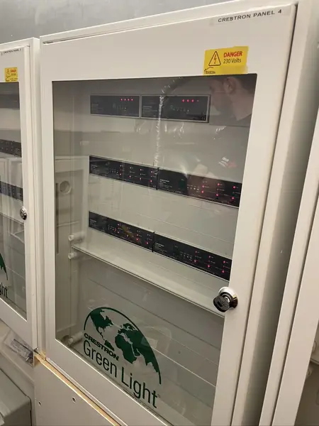 Crestron Green Light lighting control panels with dimmer modules behind a locked glass door
