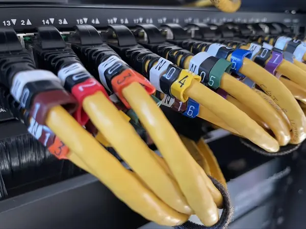 Yellow network patch leads in a PoE network switch, each with numbered colour code labels