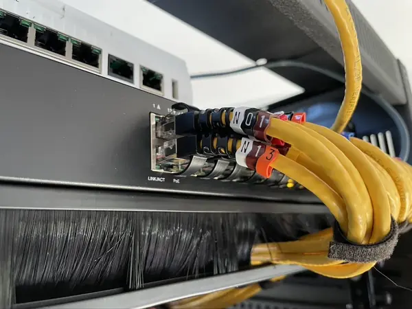 Close up of labelled network patch leads in the PoE switch, held with a hook and loop tie