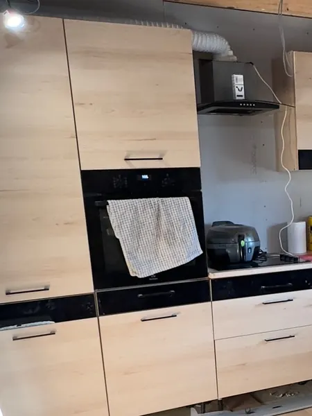 The finished cottage kitchen with pale oak units, dark worktop panels and a window above the sink