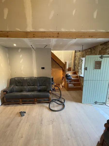 The finished living room with a leather sofa, the timber stairs and a pale blue stable door on a new timber floor