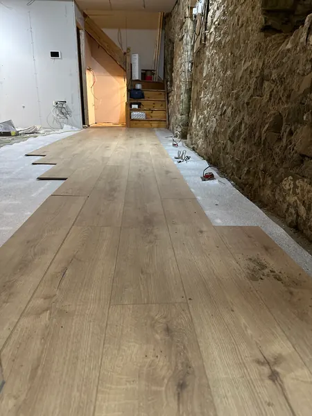 New timber floor being laid along the length of the cottage beside an exposed stone wall