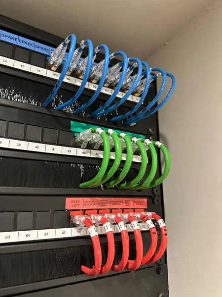 Patch panel with red leads for the cameras and front door intercom, labelled by location, and green leads for the office
