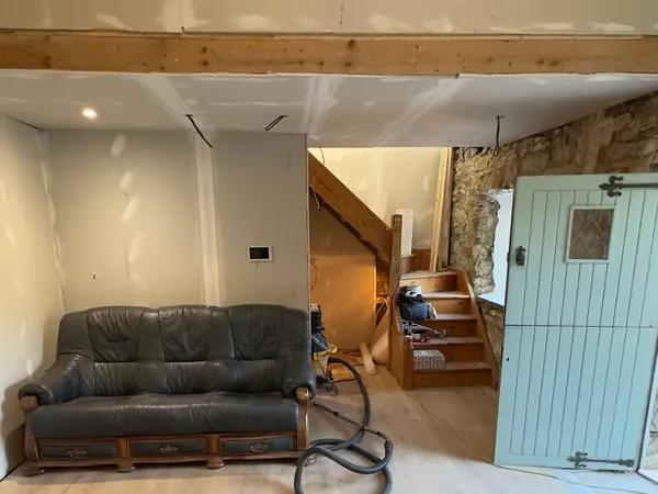 The finished living room at Ivy Cottage in Roscommon, a leather sofa, the timber staircase and a duck egg blue stable door on the new timber floor