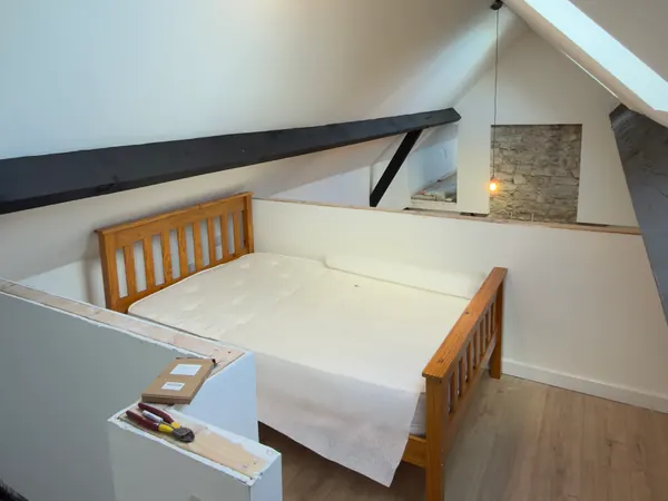 The finished bedroom under the eaves at Ivy Cottage in Roscommon, a timber bed under white sloping ceilings and a roof window