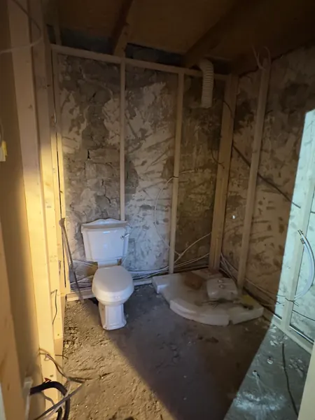 The bathroom framed out in timber against the stone wall, with a toilet pan waiting to be fitted