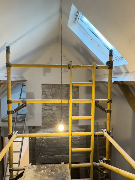 The vaulted ceiling plastered and painted white, with a scaffold tower under the roof window
