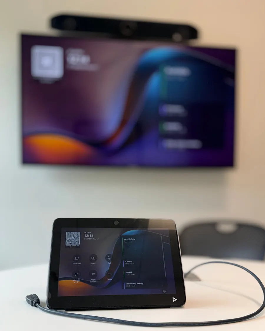 AV break fix support Limerick: Poly touch controller and cable on a meeting room table, with a wall mounted display and video bar behind