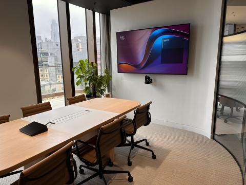 Meeting room with a wall display, a camera beneath it and a touch controller on the table