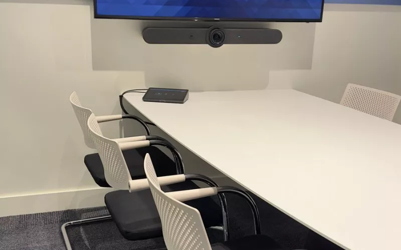 Meeting room video bar installation in Dublin, with a Logitech video bar fixed below a wall display, above a white table and white chairs