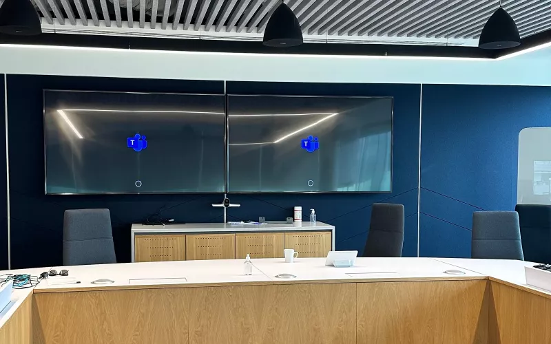 Boardroom AV installation in south Dublin, with twin wall displays showing the Microsoft Teams logo above a table with an oak veneer front