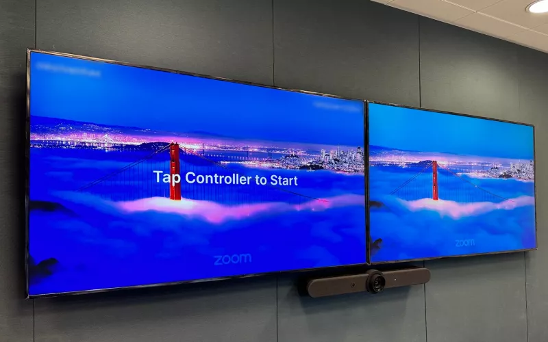 Zoom Rooms installation in Dublin: two wall displays side by side showing the Zoom logo, the left one with the message Tap Controller to Start, and a video bar below