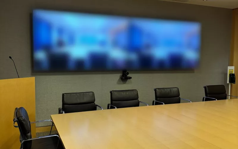 Boardroom video conferencing in Dublin, with twin screens on the end wall, a camera below them and a long timber table with black leather chairs