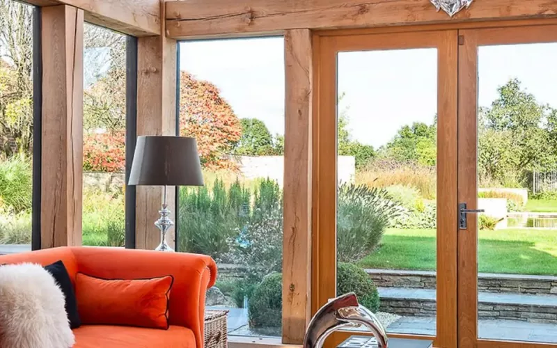 Oak framed living room with orange sofas and garden views, the sort of room a Crestron Configure Pro installer sets up