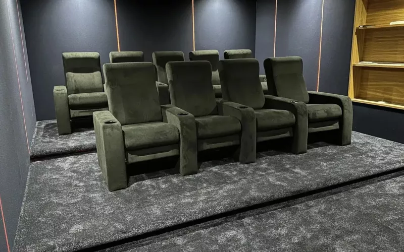 A finished home cinema room with two rows of recliners, fabric walls and fitted shelving