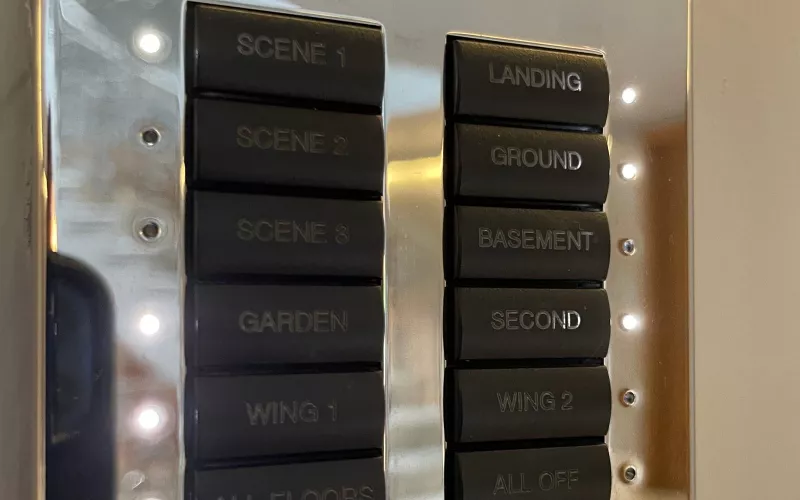 Polished chrome keypad engraved for lighting scenes and each floor, the kind of wall control used when Crestron DIN modules handle the dimming in a central panel