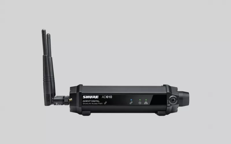 Shure Axient Digital AD610 ShowLink access point in black, seen side on with its two antennas raised on the left and three status lights on the front panel, against a pale grey backdrop