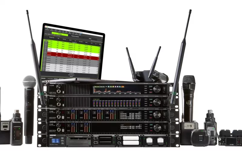 Shure Axient Digital family on white: AD600, ANX4, AD4Q and AD4D units and an SBRC charger stacked in a rack, an AD610 and a laptop showing Wireless Workbench on top, with handhelds, bodypacks, plug on transmitters, an ADX1M and an ADX5D either side