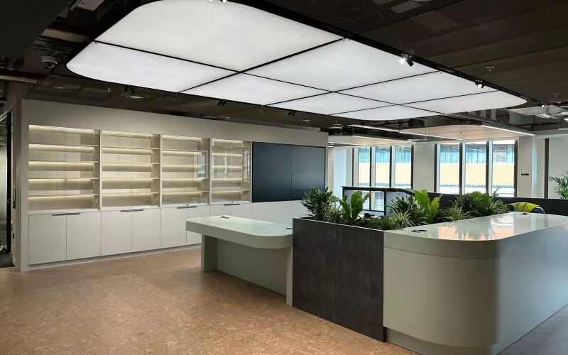 Office reception with a curved lightbox ceiling, track spotlights and lit display shelving, the sort of entrance where face recognition access control sits beside the door