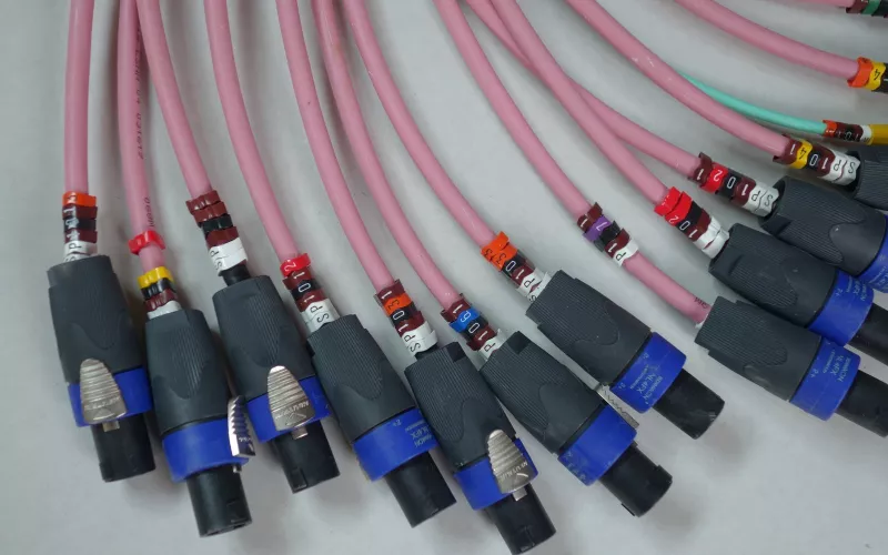 Pink speaker cables with numbered sleeves and locking connectors, laid out ready for the rack, the kind of labelled speaker wiring a self build should finish with