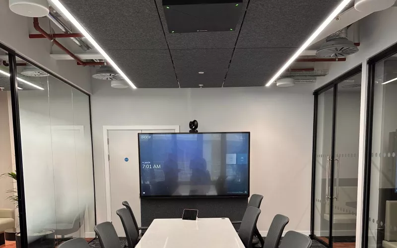 Avocor display with a camera on top in a conference room with a long white table and ceiling microphone, the equipment AV support KPIs are measured against