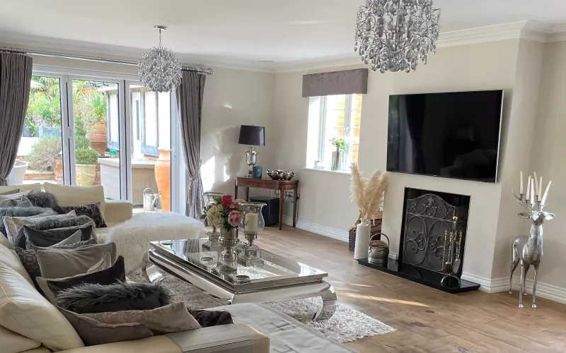 Living room with a wall mounted TV above the fireplace and no cables on show, pendant lights and folding doors to the garden, the finish that good TV wiring gives