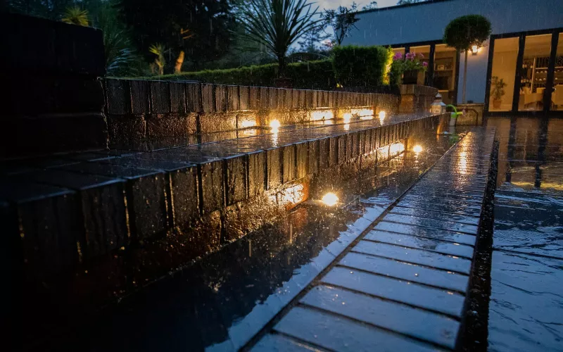 Low level lights set into a brick garden wall and steps at dusk, outdoor cabling laid with the groundworks, as EV charger wiring should be