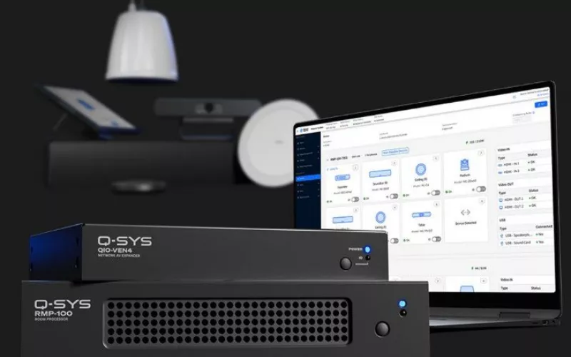 Q-SYS Teams Rooms modular kit: black RMP-100 room processor and QIO-VEN4 network AV expander, a laptop showing the RoomSuite Manager screen, and a pendant loudspeaker and camera behind