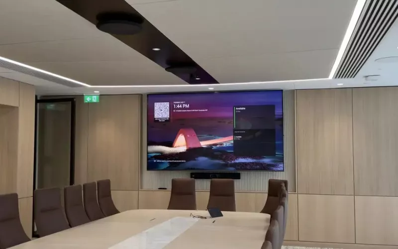 Boardroom with timber panelled walls, a large display over a video bar and round ceiling microphones, a single screen room that Cross-Platform Meeting Connect would help on Teams and Zoom calls