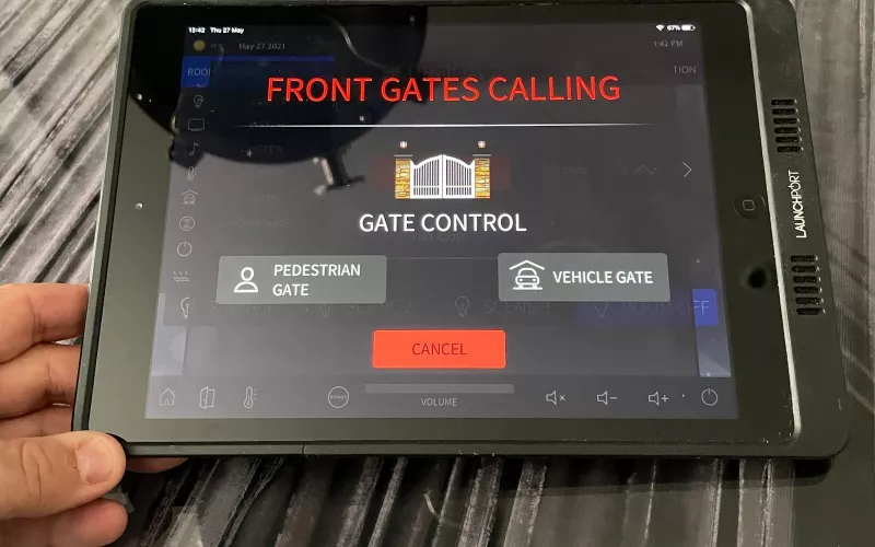 Wall touch panel answering a video intercom call from the front gate, with separate buttons to open the pedestrian gate or the vehicle gate