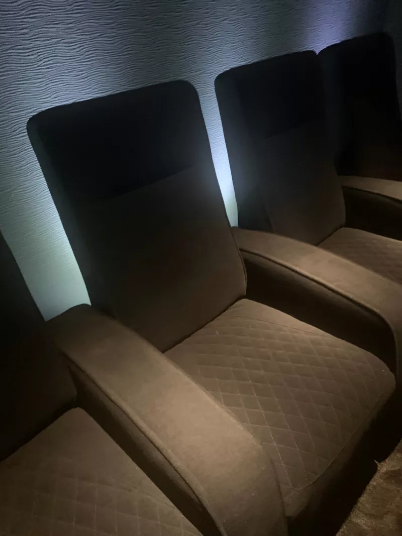 One recliner up close, its cushions quilted in a diamond pattern and pale light on the wall behind