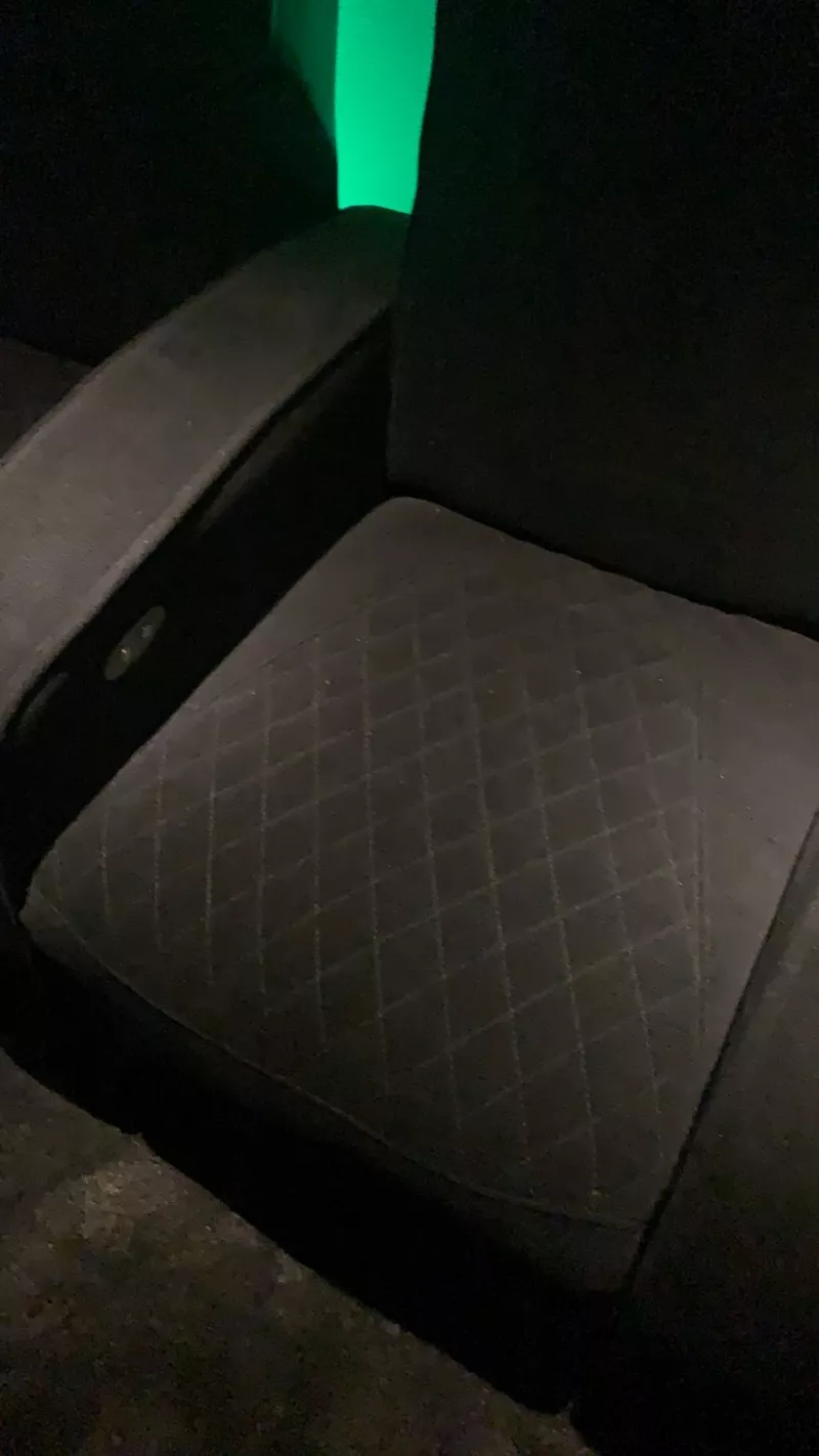 Green glow from the back wall falling across the stitched pattern of a seat
