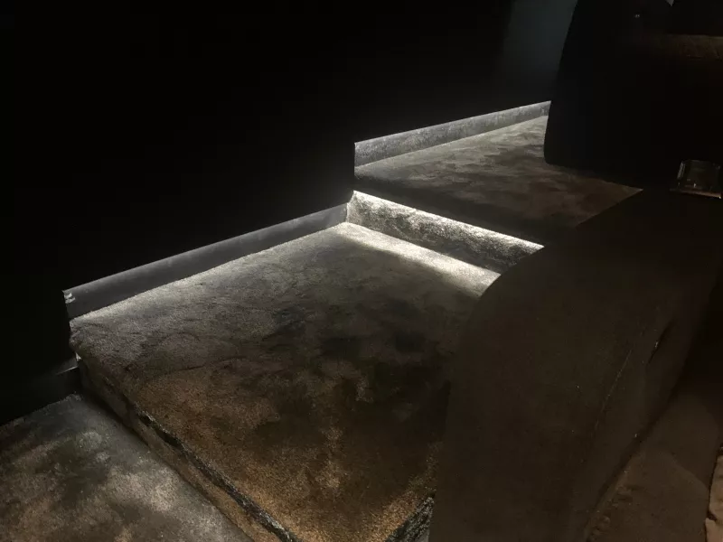 A thin LED strip tracing the nosing of a carpeted cinema step, so the edge shows up in the dark