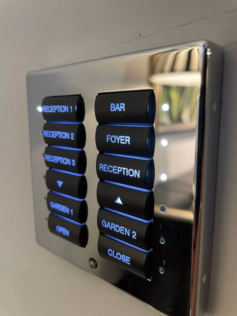 Lighting keypads done properly: a chrome plate whose engraved labels for the reception rooms, the bar, the foyer and the garden glow blue