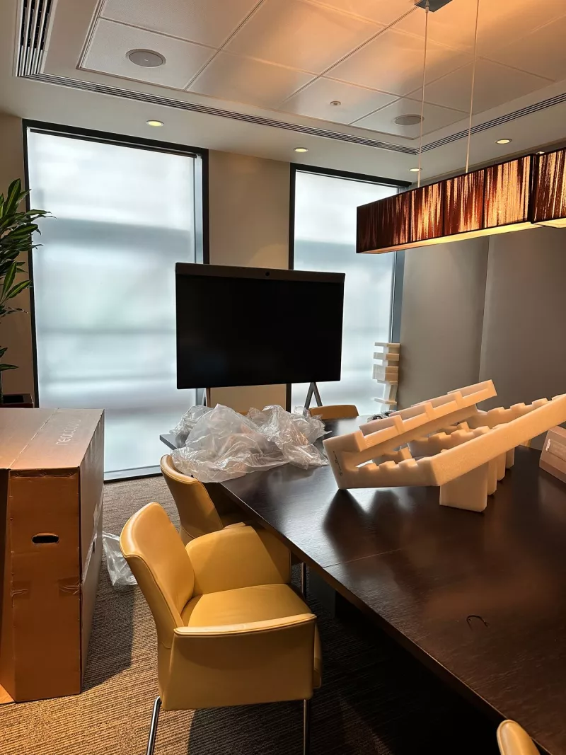 The Neat Board standing at the end of the boardroom table with its box and foam packaging in the foreground
