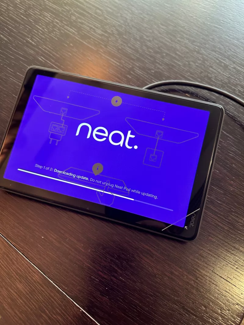 Neat Pad touch controller on the table downloading an update, with a warning not to unplug it