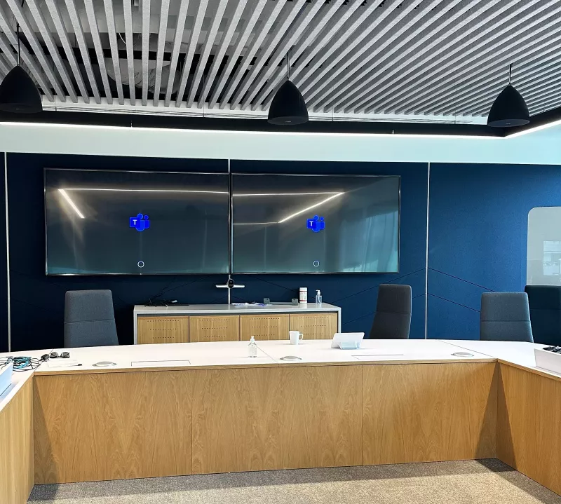 Boardroom AV installation in south Dublin, with twin wall displays showing the Microsoft Teams logo above a table with an oak veneer front