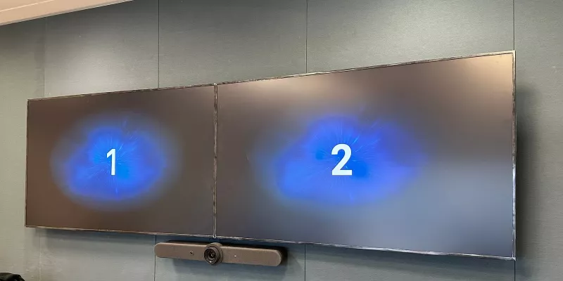 The two wall displays showing a large number each, 1 and 2, during setup, with the video bar below them