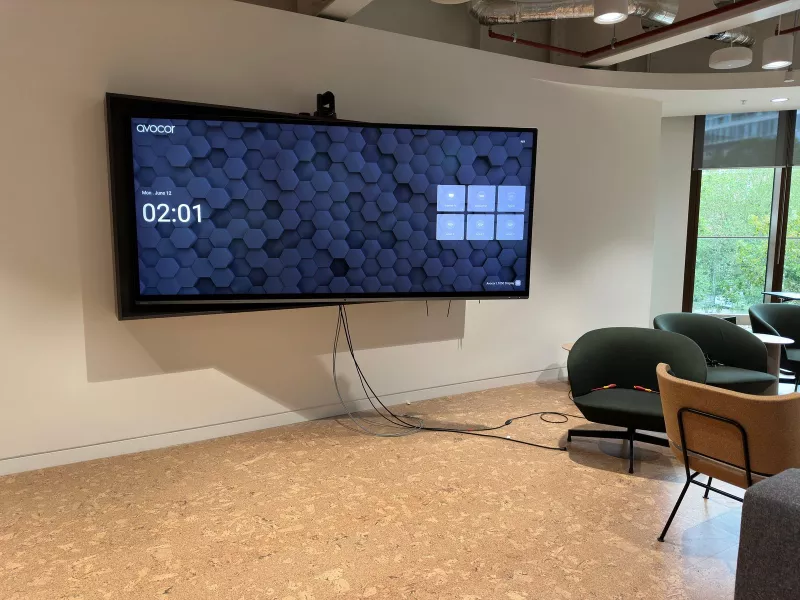 Very wide Avocor screen in the lounge showing its input choices, with a webcam sitting on top