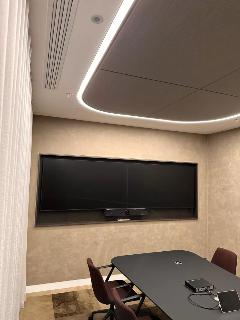 A curved line of light around a fabric ceiling panel and sheer curtains, with the twin displays at the end of the room