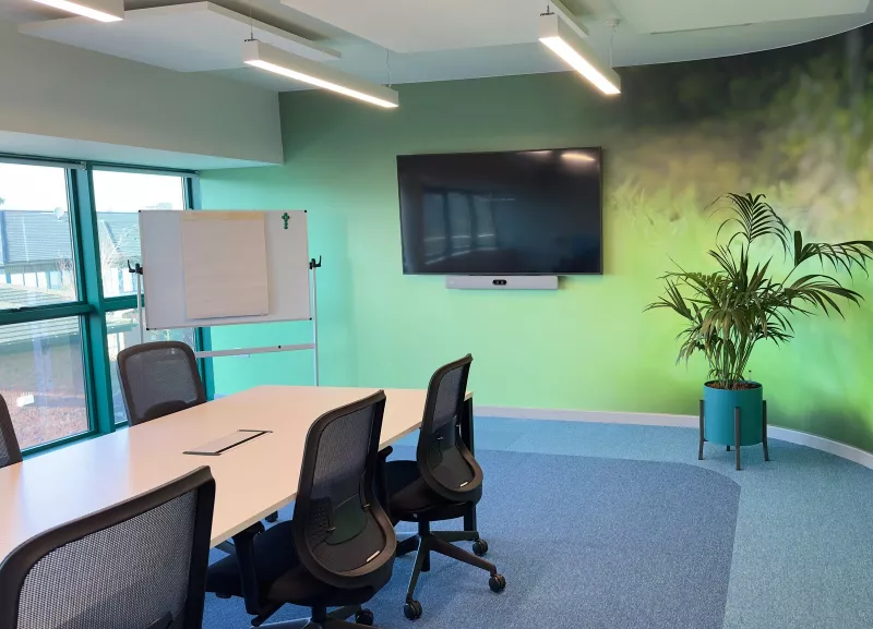 Cisco video conferencing in a meeting room in south Dublin, with a Cisco video bar under the screen, a long white table and a curved green feature wall