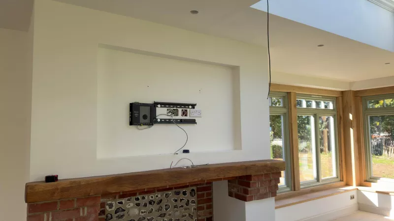 The empty recess above the fireplace with a flat bracket, back boxes, a double socket and a small Crestron box ready for the TV