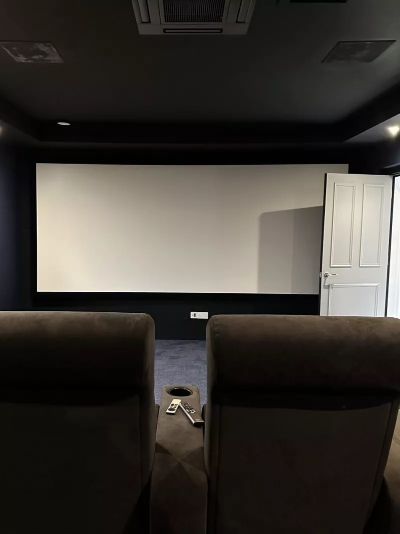 The projector screen seen from the back row of the home cinema room