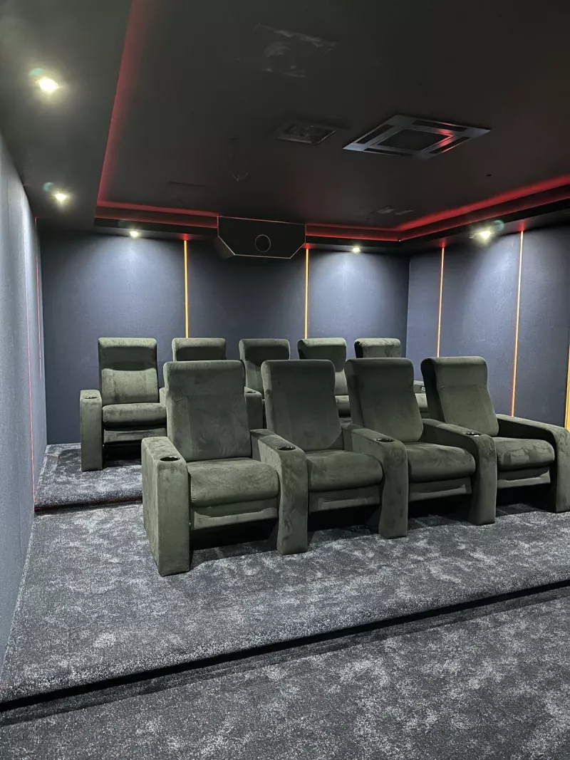Looking back from the screen at nine recliners, under a ceiling edged in red light