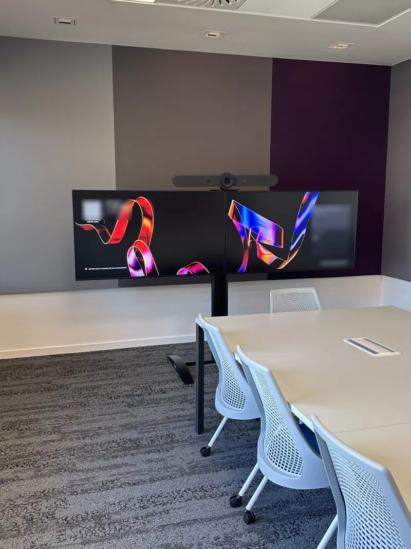 Two screens side by side under a video bar in a Dublin office meeting room