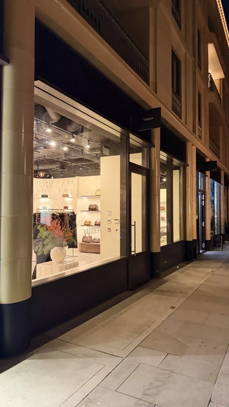 A boutique shopfront glowing onto the pavement after dark