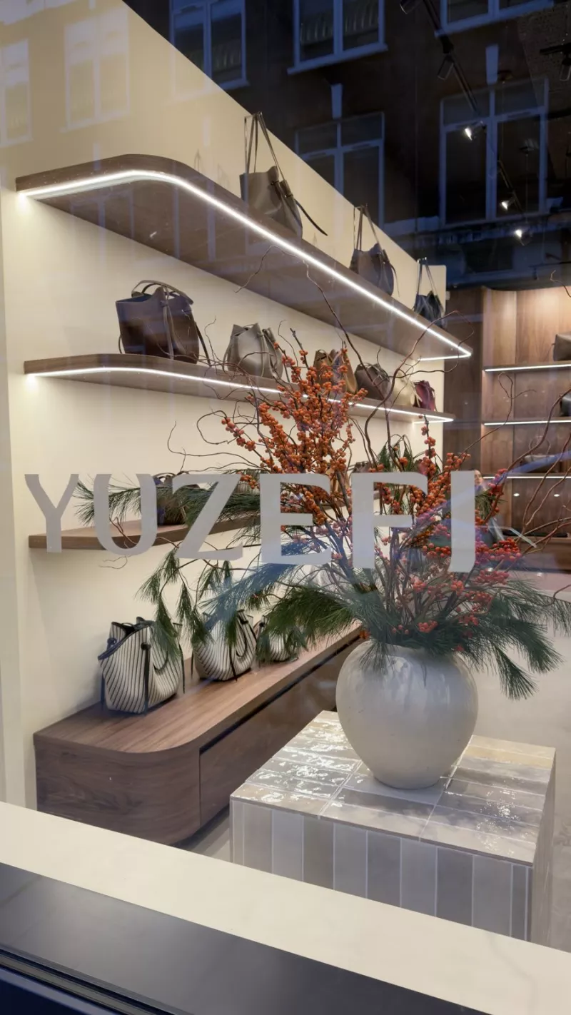 The window display seen from the street, with lit shelves behind a vase of flowers
